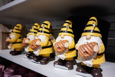 Bir dükkanda bal peteği sergilenen arılar gibi giyinmiş renkli cüceler.