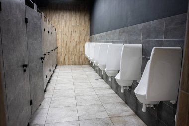 Düzenli bir düzende duvarları, pisuarları ve tezgahları olan temiz ve modern tuvalet..