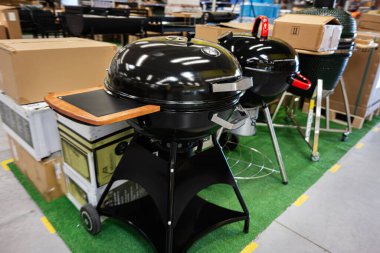 Çimenli zemini olan bir depoda gösterilen siyah barbekü ızgaraları