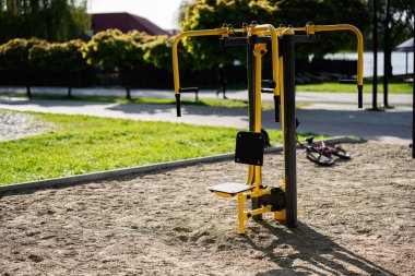 Yeşil çimenler ve açık gökyüzü olan bir şehir parkında egzersiz makinesi..