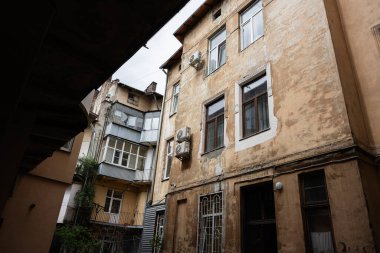 Eski dokuları, yıpranmış pencereleri ve havalandırma ünitelerini gösteren tarihi bir yapı duvarı..