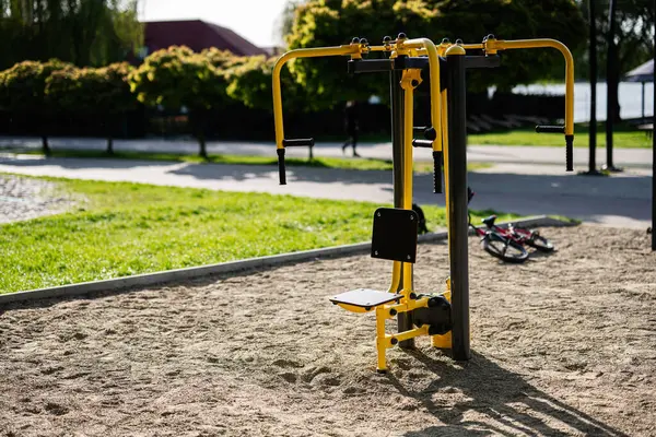Yeşil çimenler ve açık gökyüzü olan bir şehir parkında egzersiz makinesi..