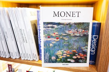 Lviv, Ukrayna - 4 Mayıs 2025: Monet 'in nilüfer çiçekleri üzerine bir kitap içeren bir kitaplık.