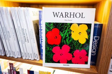 Lviv, Ukrayna - 4 Mayıs 2025: Çeşitli tasarım temalı yayınlarla çevrili organize bir rafta canlı bir Warhol sanat kitabı