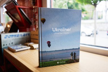 Lviv, Ukrayna - 04 Mayıs 2025: Açık hava manzaralı sert kapaklı Ukraynalı kitap, ahşap bir masanın içinde fotoğraflandı