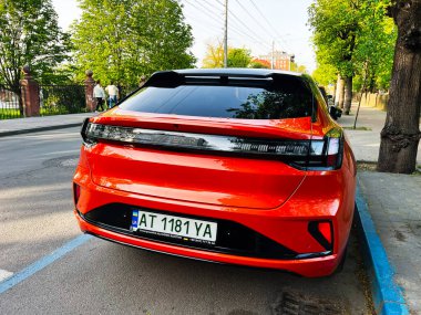 Ivano-Frankivsk, Ukrayna - 14 Mayıs 2025: Doğal ışık altında bir şehir caddesinde şık turuncu bir Zeekr 001 elektrikli araba