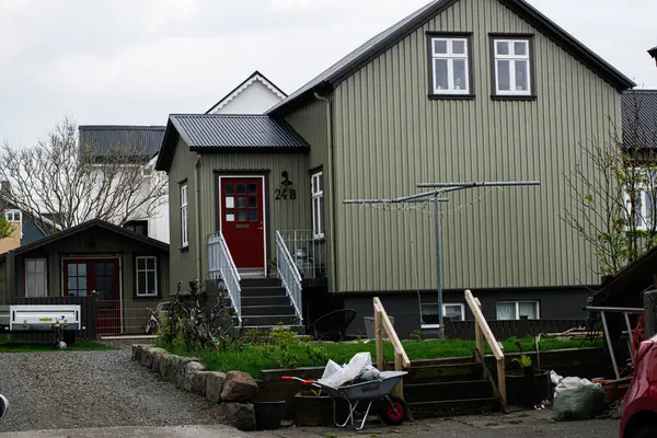 Akranes, İzlanda - 15 Mayıs 2025: Bulutların altında Akranes, İzlanda 'da bir bahçe ve garaj yolu olan ev.