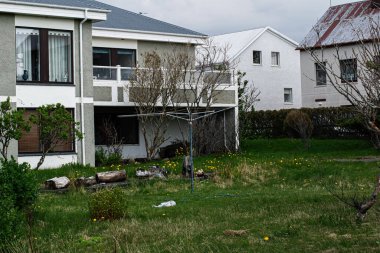 Akranes, İzlanda - 15 Mayıs 2025: Akranes 'te yeşil bahçesi, ağaçları ve kentsel çevresi olan bir ev.