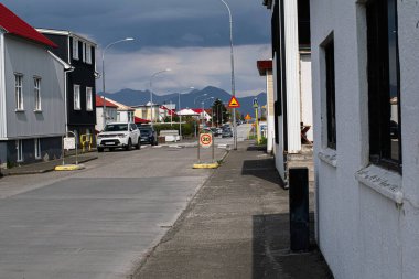 Akranes, İzlanda - 15 Mayıs 2025: Akranes, İzlanda 'da bulutlu gökyüzünün altında evler ve dağların resimli kentsel manzarası