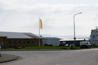 Akranes, İzlanda - 15 Mayıs 2025: Binaların, sarı bayrağın ve Akranes 'te bir arabanın yer aldığı bir sokak manzarası