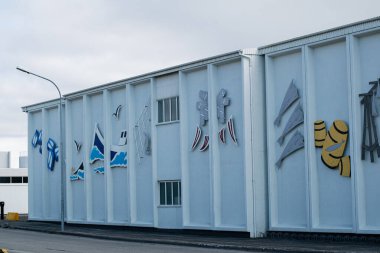Akranes, İzlanda - 15 Mayıs 2025: Akranes, İzlanda 'da renkli okyanus temalı dekorasyonlar sergilenen beyaz sanayi binası.