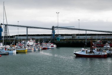 Akranes, İzlanda - 15 Mayıs 2025: Akranes, İzlanda 'da sanayi yapıları ve sakin suların yanı sıra balıkçı tekneleri kenetlendi.