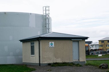 Akranes, İzlanda - 15 Mayıs 2025: Akranes, İzlanda 'da büyük bir endüstriyel depolama tankının bitişiğindeki bir kamu hizmetleri binası.