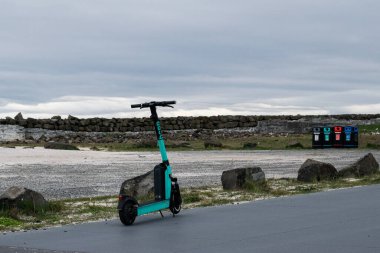 Akranes, İzlanda - 15 Mayıs 2025: Turkuaz elektrikli scooter Akranes, İzlanda 'da kıyı şeridi yakınlarında bulutlu bir günde park edildi