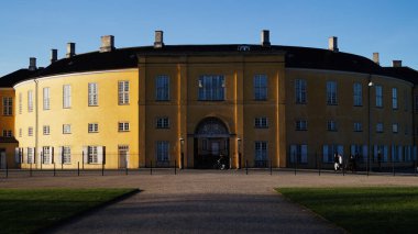 Kopenhag, Danimarka - 21 Nisan 2025: Danimarka 'da açık mavi gökyüzü altında yarı dairesel sarı bina cephesi