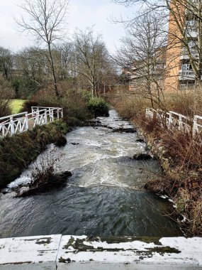 Ağaçlarla, binalarla ve çitlerle çevrili sakin bir dere manzarası. Holstebro, Danimarka
