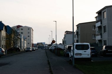 Akranes, İzlanda - 16 Mayıs 2025: Akranes, İzlanda alacakaranlıkta evleri ve park halindeki arabaları olan banliyö sokak manzarası.