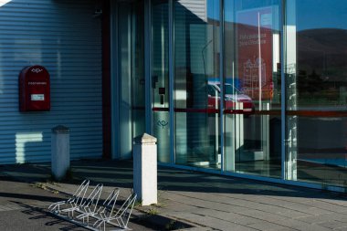 Akranes, İzlanda - 16 Mayıs 2025: Akranes, İzlanda 'da yansıtıcı cam ve park edilmiş bisikletlerle çağdaş bina cephesi