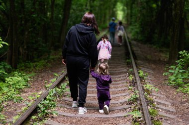 Yapraklı demiryolu raylarında yürüyen grup doğadaki birlikteliği temsil ediyor.