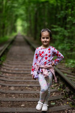 Orman yolunda neşeli bir çocuk doğa ve demiryolu zeminiyle.
