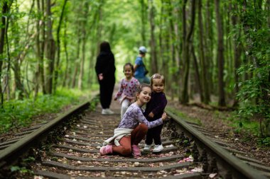 Bir grup çocuk, sakin bir orman rayında vakit geçiriyorlar.