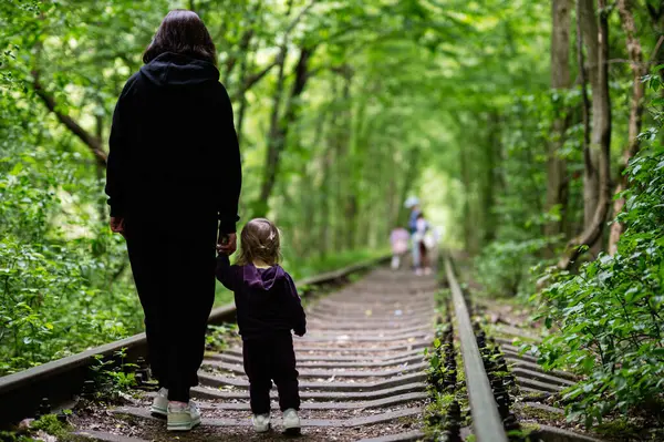 Bir anne ve çocuk yemyeşil otlaklar arasında terk edilmiş bir orman yolunda geziniyor..