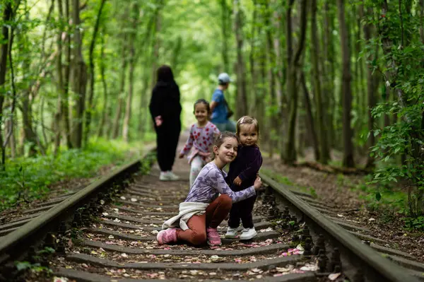 Bir grup çocuk, sakin bir orman rayında vakit geçiriyorlar.