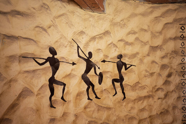 Ancient cave art depicting figures in dynamic motion, painted on a textured surface