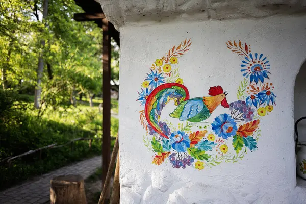 Güzel, canlı, el boyalı, beyaz duvarında çiçekler olan bir horoz tasarımı..