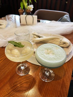 İki şık kokteyl süslenmiş ve dekorlu ahşap bir masaya kurulmuş.