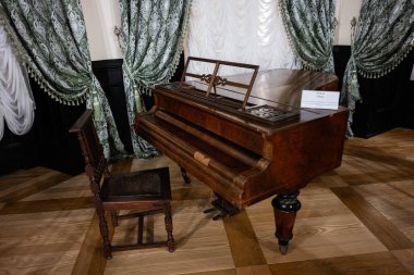 Zbarazh, Ukrayna - 30 Mayıs 2025: Geleneksel mobilyalı bir salonda zarif bir antik ahşap piyano ve sandalye