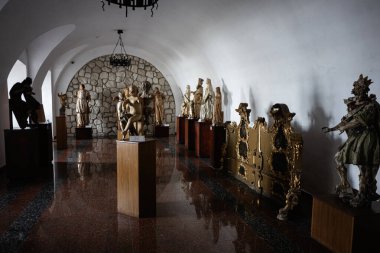 Zbarazh, Ukrayna - 30 Mayıs 2025: Parlak zeminli kemerli bir koridorda sergilenen altın ve taş heykeller