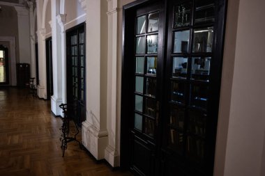 Zbarazh, Ukrayna - 30 Mayıs 2025: Ahşap zemin, yüksek kapılar ve ince ışıklandırmalı kemerli mimari içeren bir koridor.