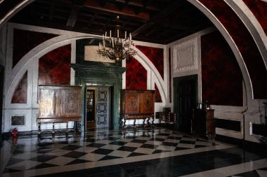 Zbarazh, Ukrayna - 30 Mayıs 2025: Dekoratif mobilyalar, kırmızı duvarlar ve karmaşık mimari unsurların yer aldığı zarif tarihi iç mekan.