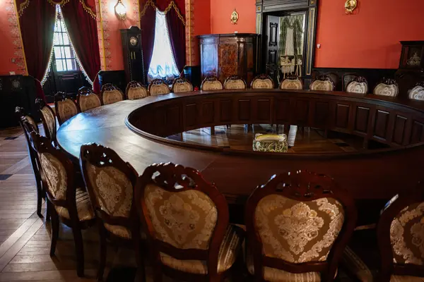 Zbarazh, Ukrayna - 30 Mayıs 2025: Dairesel masa, süslemeli sandalyeler ve klasik ahşap mobilyalar.