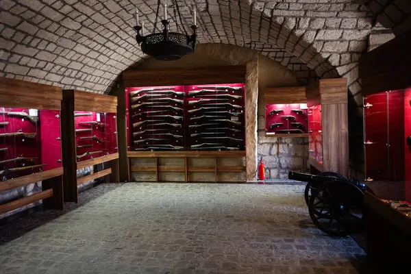 Zbarazh, Ukrayna - 30 Mayıs 2025: Tarihi görüntülerin yer aldığı taş duvarlı bir odada klasik ateşli silahlar sergileniyor.