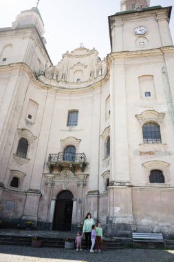 Bir aile, tarihi bir katedralin önünde taş basamaklarda poz veriyor..