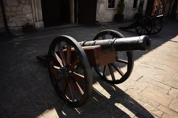 Dışarıda, güneş ışığıyla aydınlatılan taşların üzerinde sergilenen tarihi ahşap top.