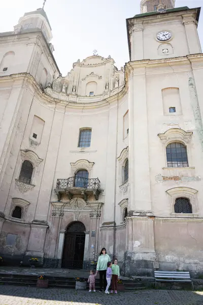 Bir aile, tarihi bir katedralin önünde taş basamaklarda poz veriyor..