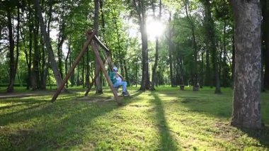 Mutlu çocuklar güzel güneşli bir günde parkta sallanıyor..