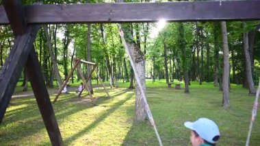 Çocuklar güneşli bir günün tadını çıkarırlar parkta sallanırken.