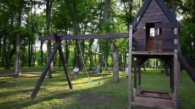 Mutlu çocuklar parkta salıncaklarda ve oyun parklarında oynuyorlar..