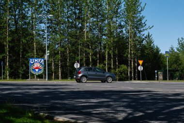 Mosfellsbr, İzlanda - 09 Haziran 2025: güneşli gökyüzünün altındaki yeşil ağaçlarla çevrili bir otoparkta araç. Ungmennaflagi Afturelding. 