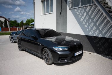 Kyiv, Ukrayna - 10 Haziran 2025: Siyah lüks bir BMW 5 serisi G30 sedan açık bir gökyüzünün altında bir binanın yanına park edilmiş.