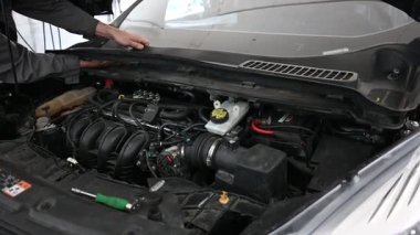 Tamirci arabanın motorunu kontrol ediyor. Otomatik onarım servisi.
