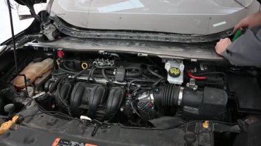 Tamirci Oto Tamirhanesinde Araba Motoru üzerinde çalışıyor