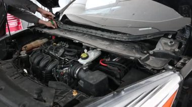 Tamirci Oto Tamirhanesinde Araba Motoru üzerinde çalışıyor