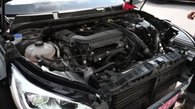 Mekanikler kaputun altındaki bir araba motorunu inceliyor, tamiratları tartışıyorlar..