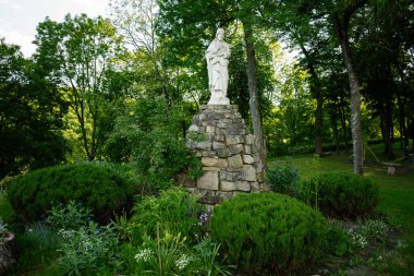 Beyaz mermer bir heykel. Yüce İsa heykeli. Serin yeşil bir bahçedeki taş bir heykel üzerinde..