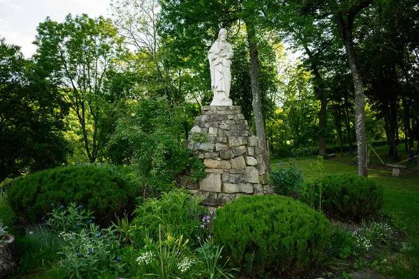 Beyaz mermer bir heykel. Yüce İsa heykeli. Serin yeşil bir bahçedeki taş bir heykel üzerinde..